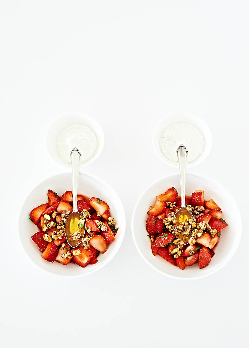 Moderne Food-Fotografie leckeres Dessert mit frischen Erdbeeren, karamellisierten Nüssen und Honig auf weißem Tisch mit viel Freiraum